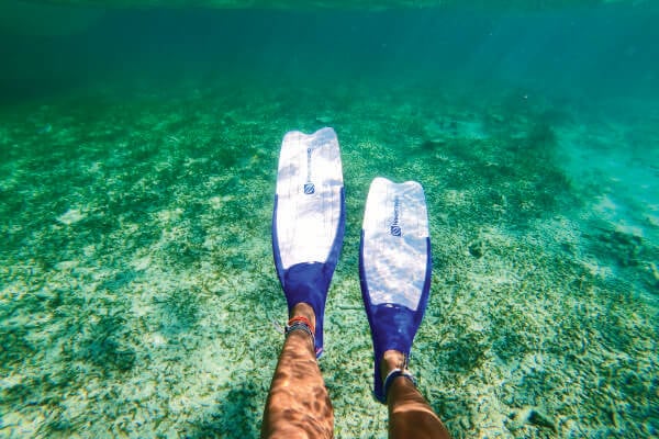 Woman with swim fins resting her feet in the water on a Saltwater Seafari boat tour