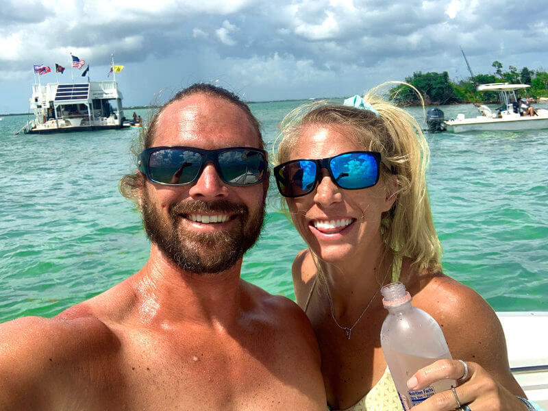 Photo of Matt and Jennifer Parramore doing a selfie. They have their backs to the Florida Keys water, have sunglasses on and are smiling at the camera.