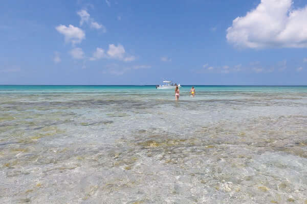 Photo of two young ladies walking through a sandbar to get back into the deeper water where the Saltwater Seafari is anchored.